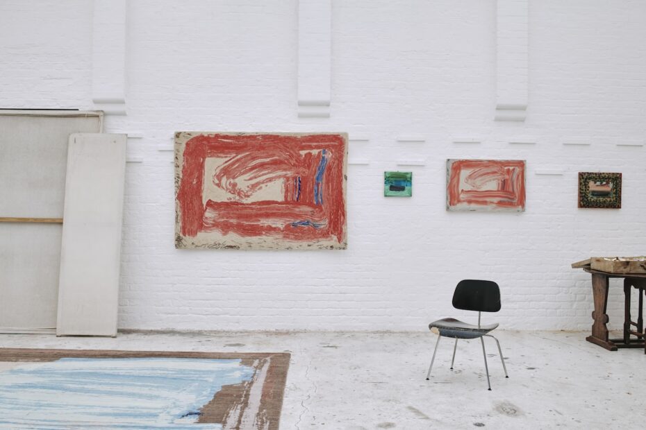 Howard Hodgkin Home limited-edition rug based on “Red Sky in the Morning” (2016) hanging alongside the original painting in the artist’s studio, London, 2023