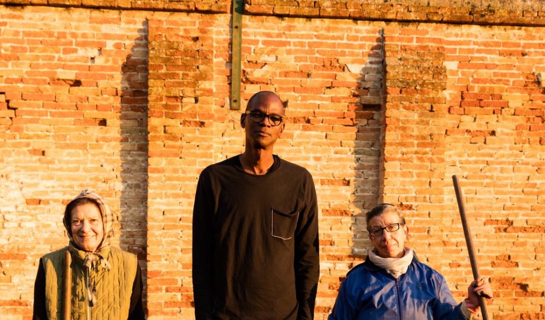 Co-op participant standing in the garden (left and right), Mark Bradford (central).Casa Reclusione per Donne Giudecca, Venice.November 30, 2016.Photo by Agata Gravante.Courtesy of the artist.