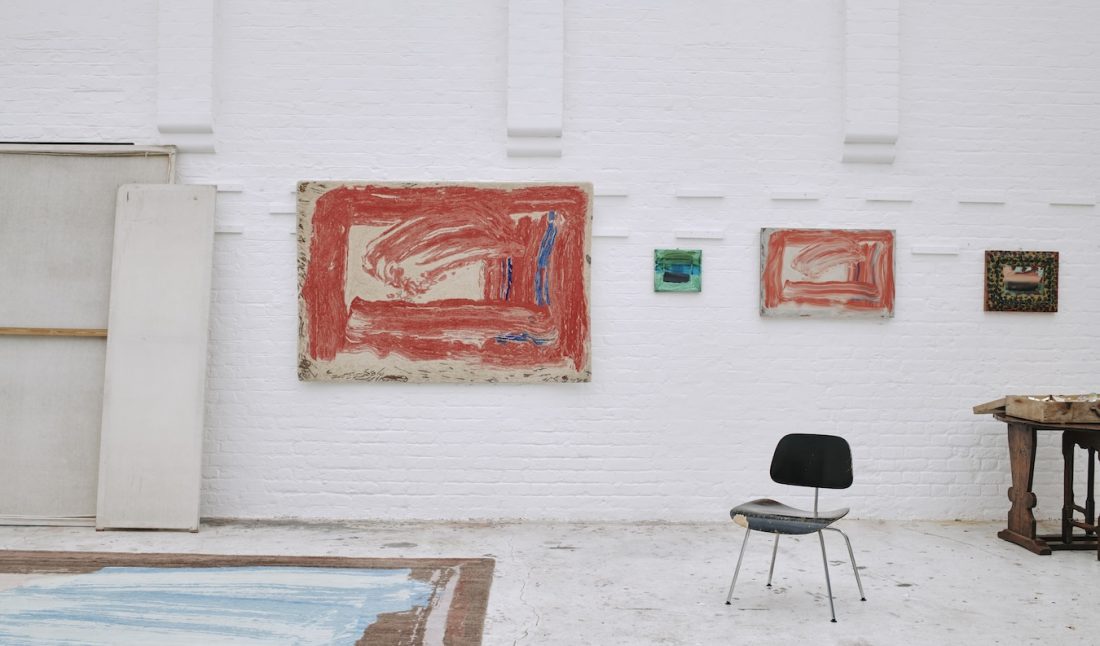 Howard Hodgkin Home limited-edition rug based on “Red Sky in the Morning” (2016) hanging alongside the original painting in the artist’s studio, London, 2023